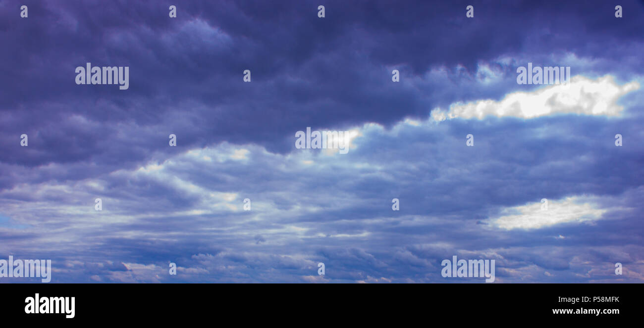 Despite dark clouds, on the blue sky  sun shines. Stock Photo
