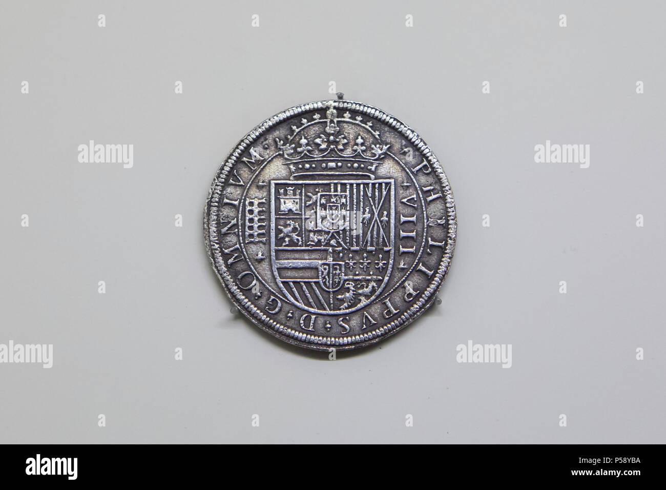 Spanish dollar of King Philip II of Spain. Spanish silver coin also known as the Real de a Ocho or the Piece of Eight minted in Segovia (1597) on display in the National Archaeological Museum (Museo Arqueológico Nacional) in Madrid, Spain. The great coat of arms of the Hispanic Monarchy is depicted in the coin. The Roman aqueduct is depicted in the left as the mark of the Segovia Mint and as the city's most iconic monument. Stock Photo