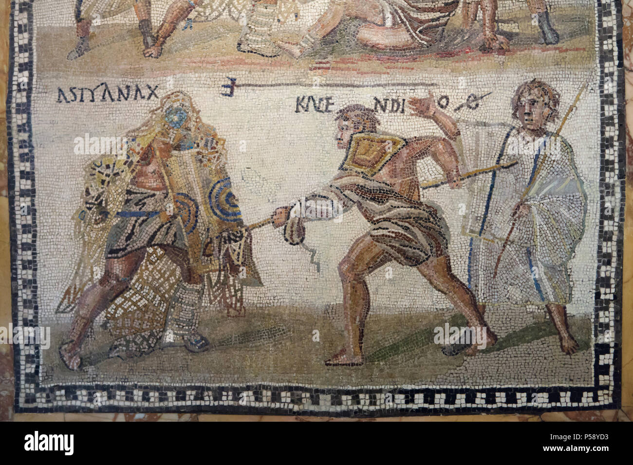 Gladiator fight depicted in the Roman mosaic from the 3rd century AD on display in the National Archaeological Museum (Museo Arqueológico Nacional) in Madrid, Spain. The secutor (Roman armed gladiator) fighting versus the retiarius (Roman net fighter). According to the Latin inscription, the secutor Astyanax and the retiarius Kalendio are engaged in mortal combat. The lanista (gladiator trainer) cheers them on. The outcome is confirmed by the inscriptions: the word VICIT appears beside Astyanax, and beside Kalendio's name is an O with a line through it, an abbreviation for Obiit or Death. Stock Photo