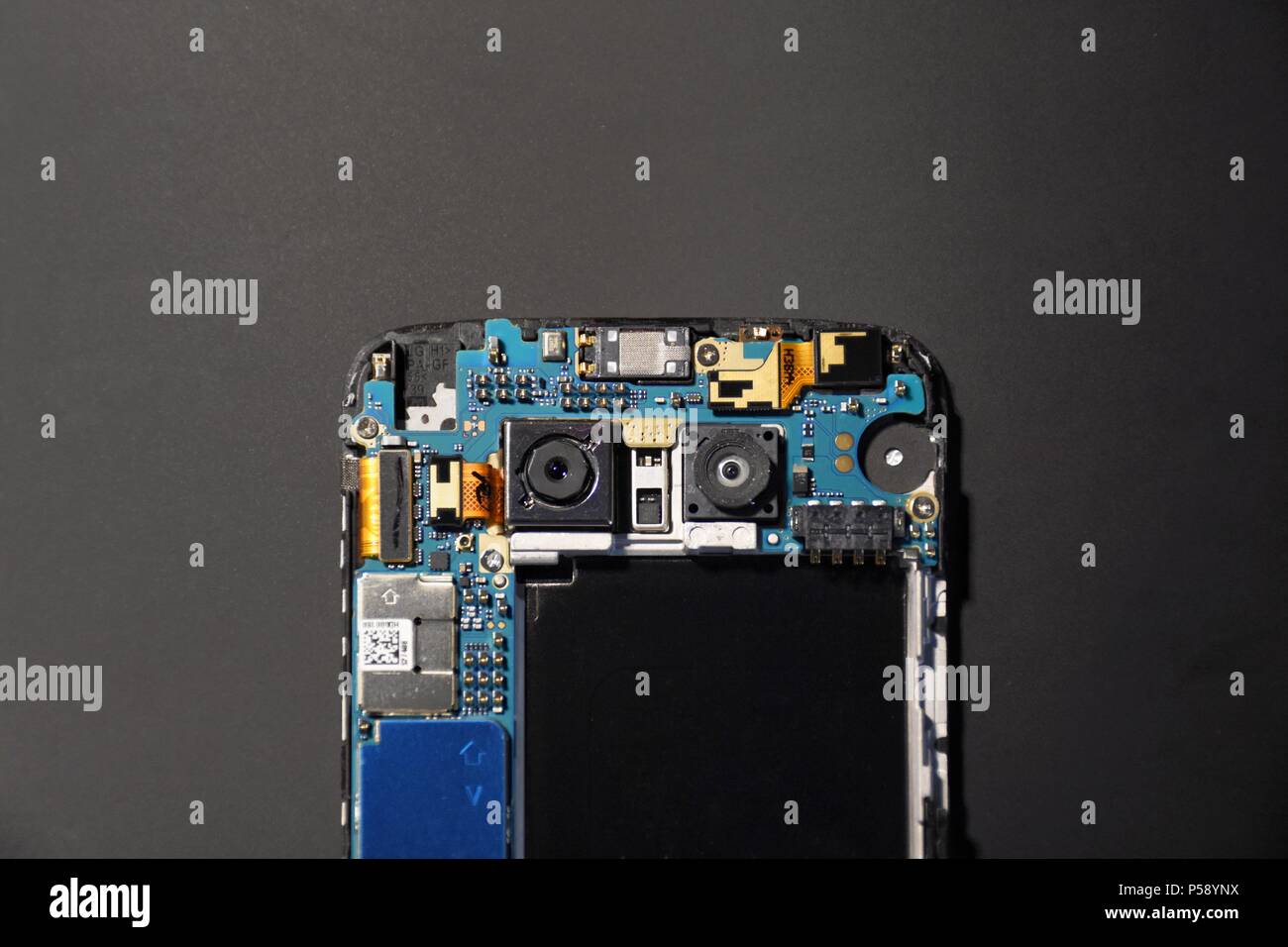 An LG G5 under repair, showing off its unique dual camera setup and the beautiful motherboard design within. Stock Photo