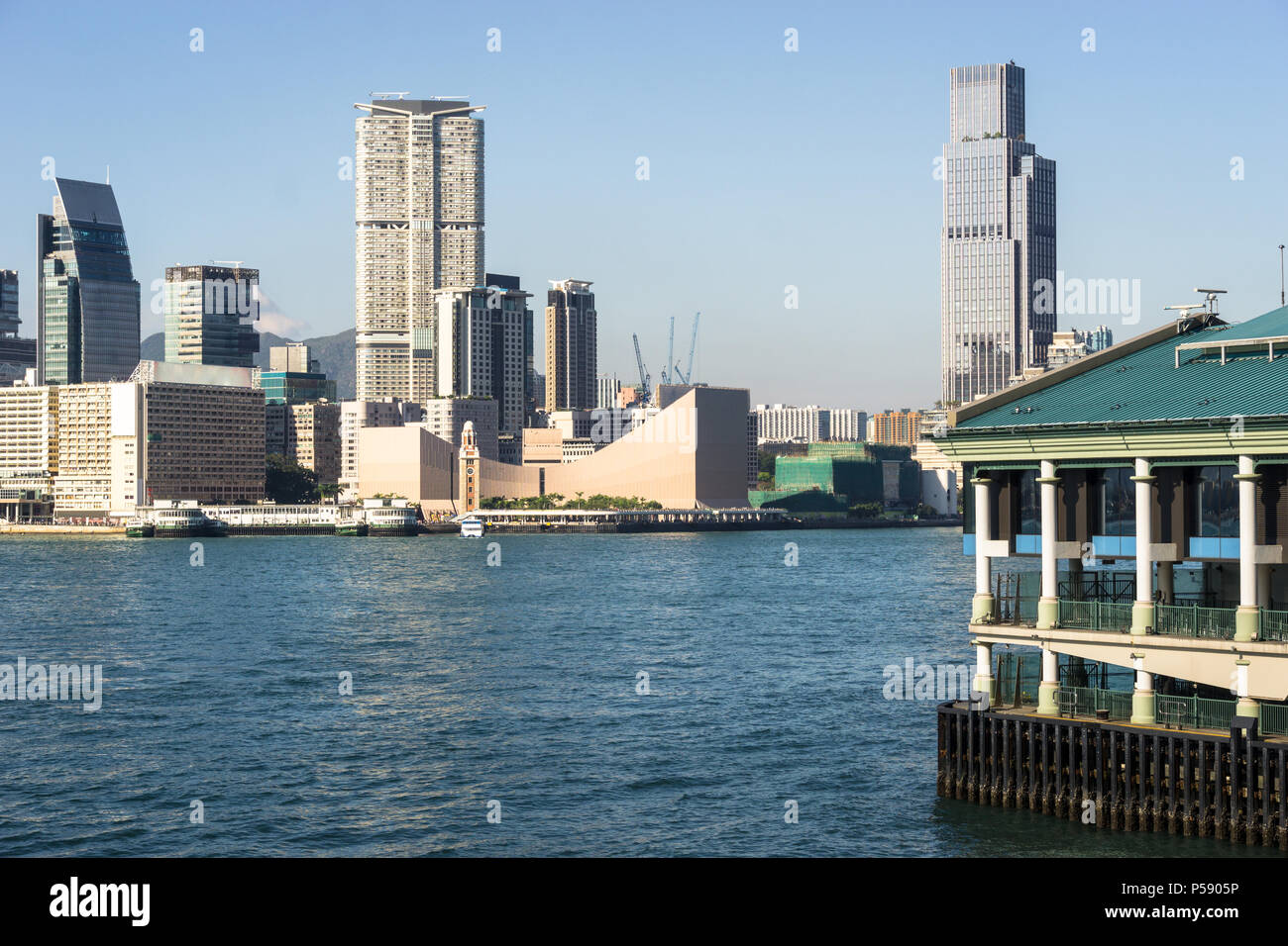 Central Star Ferry pier with the Kowloon skyline at Tsim Sha Tsui view from across the Victoria harbour in Hong Kong on a sunny day in China SAR. Stock Photo