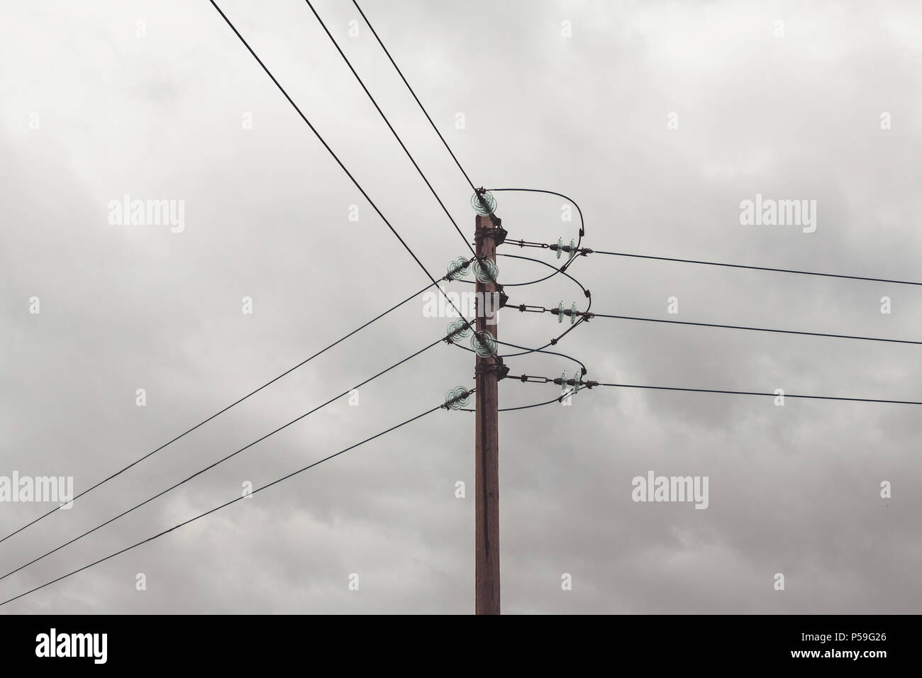 Electrical power lines going in three directions on a grey cloudy day ...