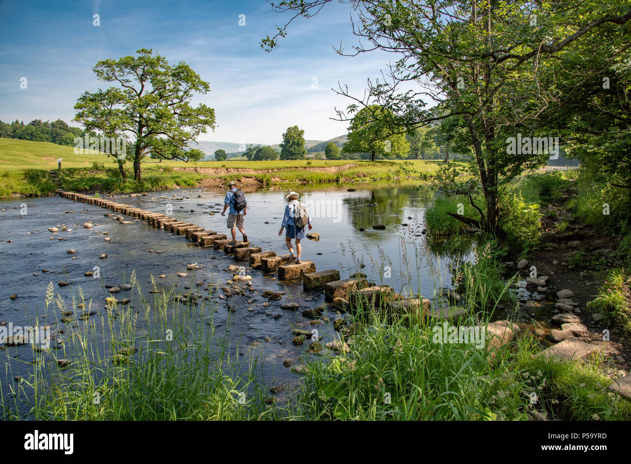 Whitewell, Clitheroe, Lancashire, UK. 26th June, 2018. Walkers negotiating the stepping stones over the river Hodder at Whitewell, Clitheroe, Lancashire on a day where temperatures are expected to reach 27 plus. Credit: John Eveson/Alamy Live News Stock Photo