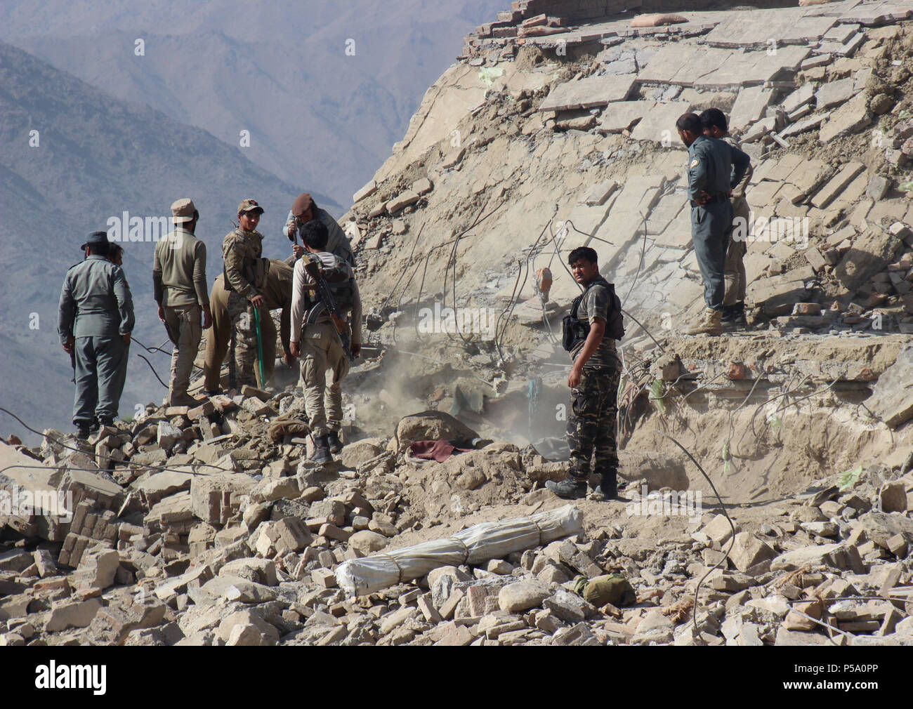 Asadabad, Afghanistan. 26th June, 2018. Afghan security force members inspect the site of a suicide attack in Chawkay district of Kunar province, Afghanistan, June 26, 2018. Some nine police personnel were killed
