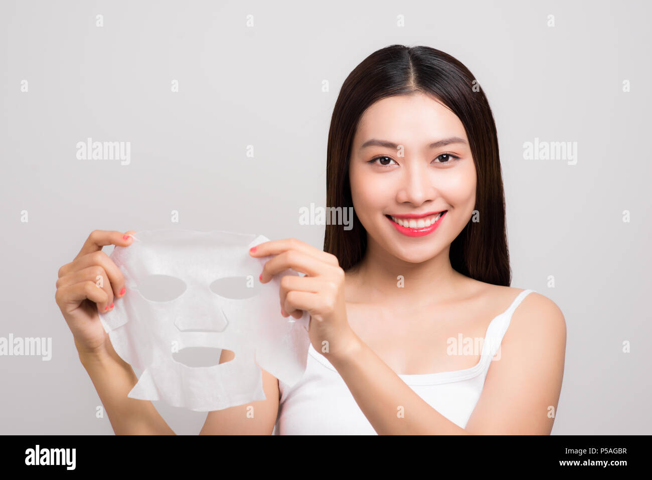 Beautiful asian woman applying paper sheet mask on her face white ...