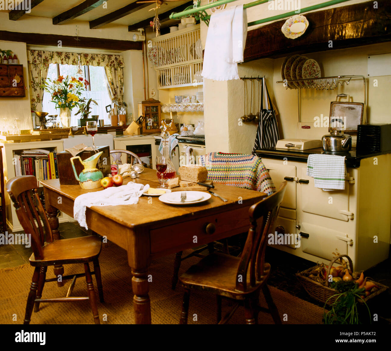 Vintage pine chairs and table in old fashioned cottage kitchen with cream Aga Stock Photo
