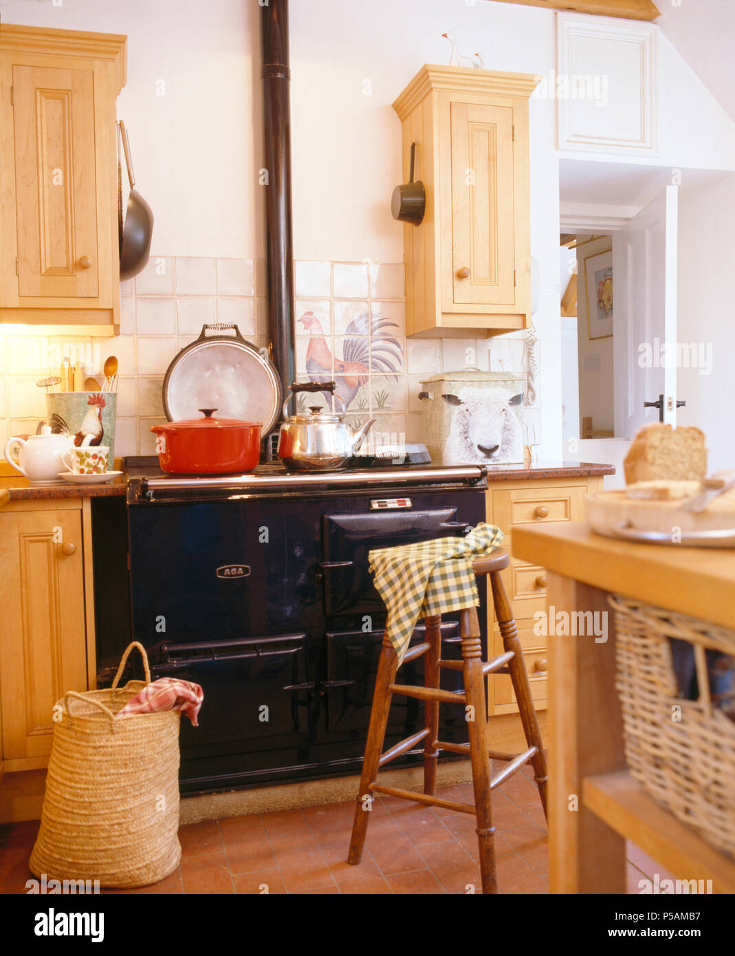 Pine wall cupboards above black Aga in cottage kitchen Stock Photo