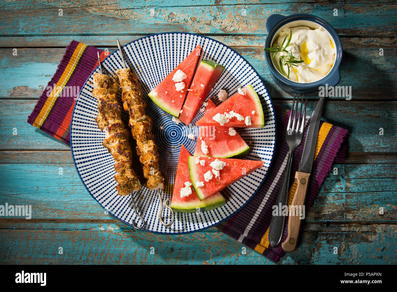 Souflaki - 2 gegrillte Schweinespieße mit Wassermelone, Feta und Knoblauch-Creme Stock Photo
