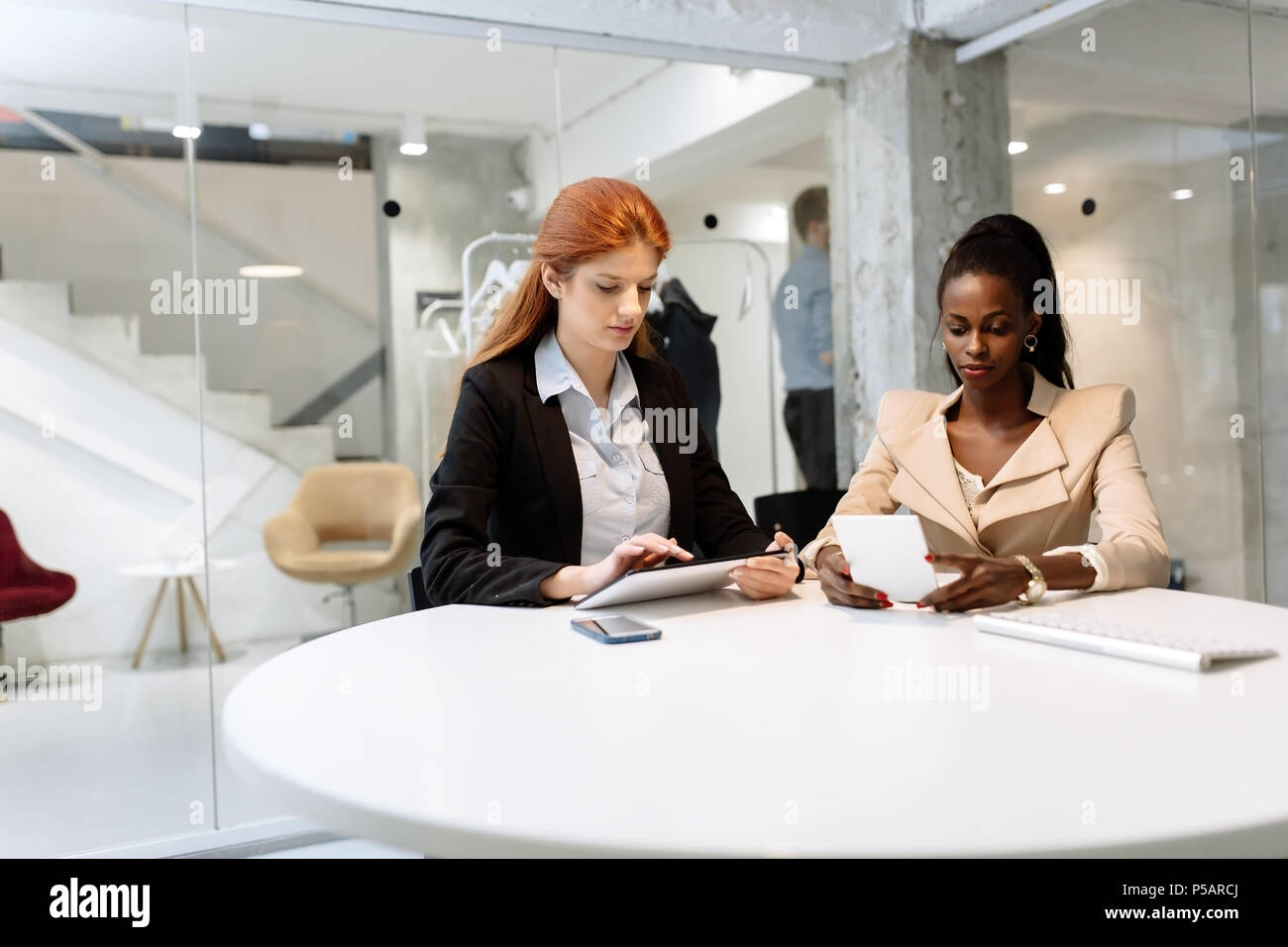 Two attractive businesswomen using technology Stock Photo