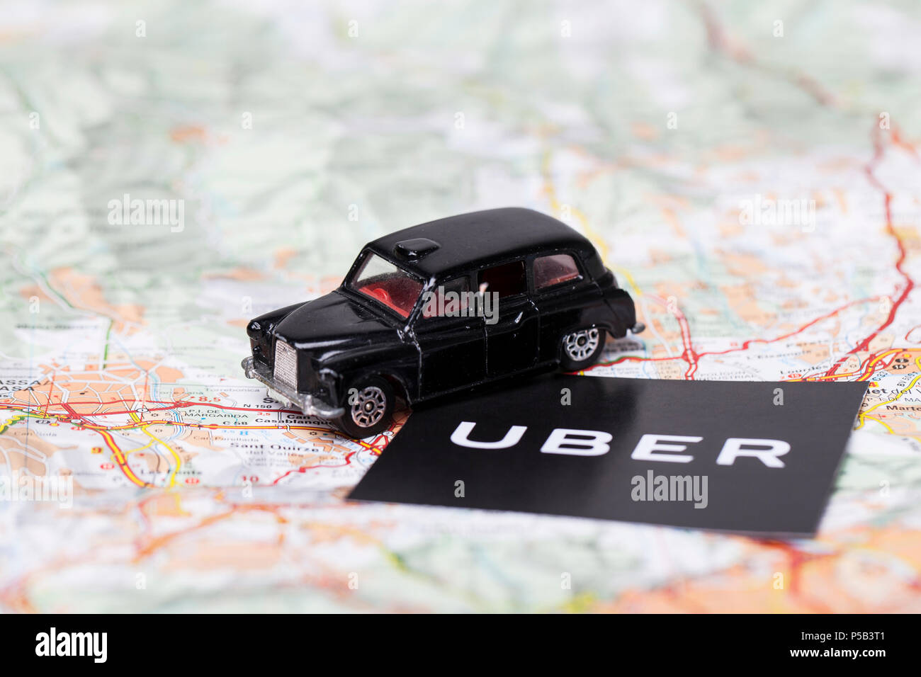 London, UK - MARCH 23rd 2017: A photograph of the Uber logo with a black London style taxi toy car. Uber is a popular taxi style transport service app Stock Photo