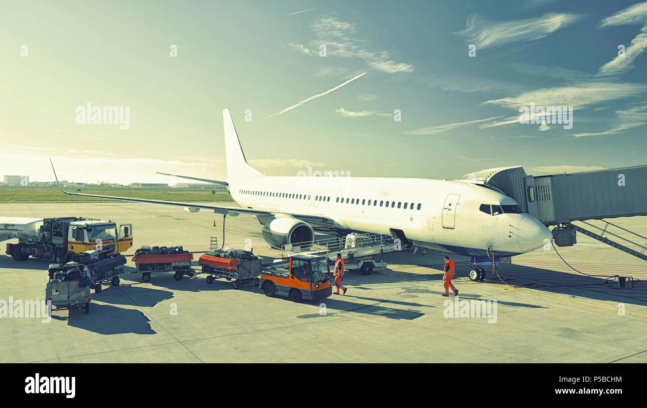 ground staff handling an aircraft before departure at the airport - loading luggage Stock Photo