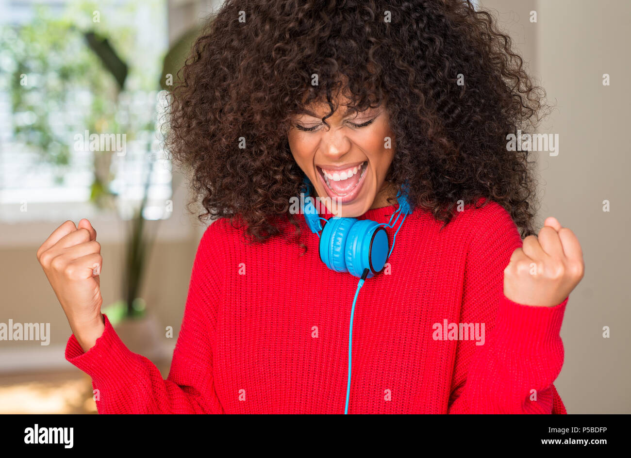 African american woman wearing headphones very happy and excited doing ...