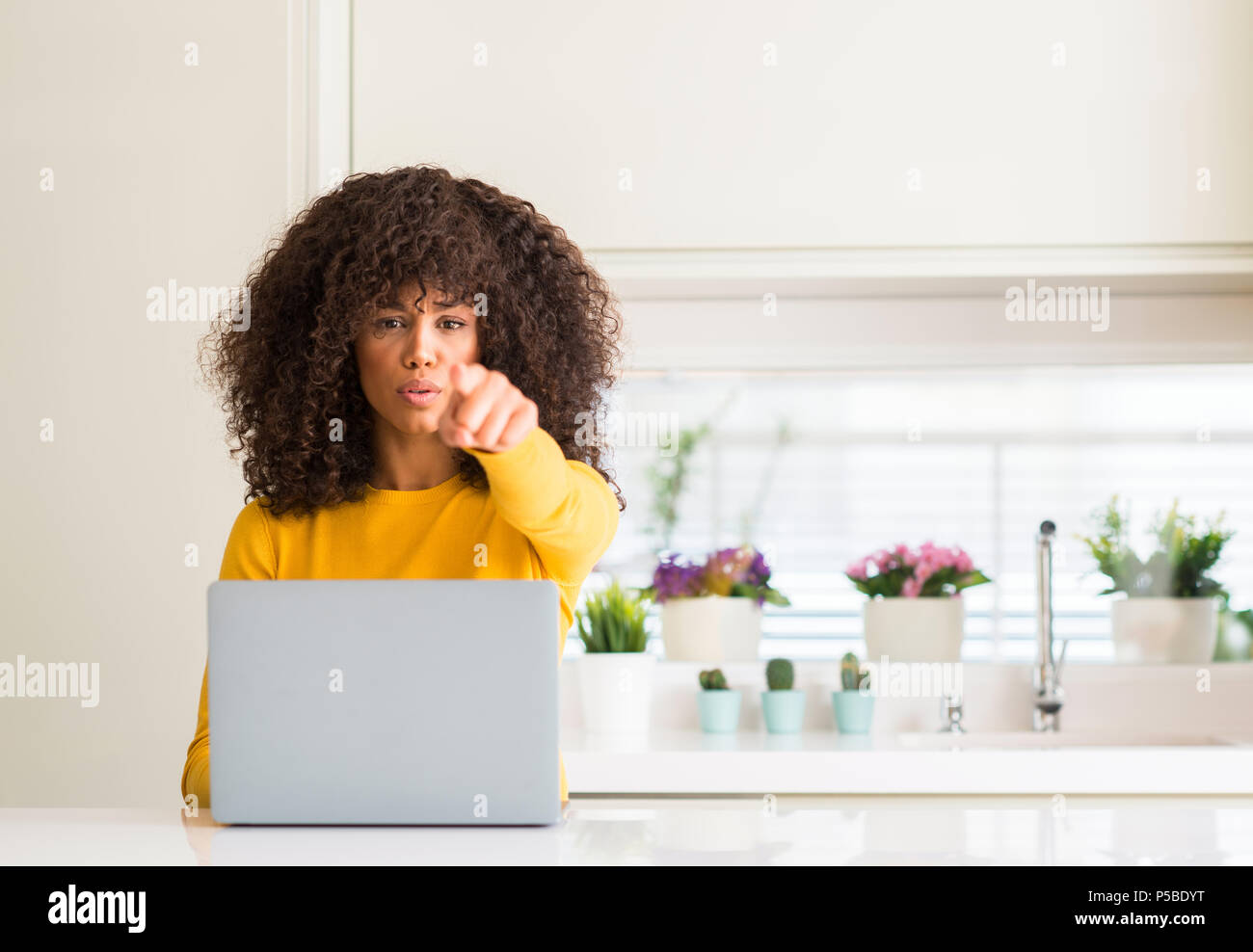African american woman using computer laptop at kitchen pointing with ...
