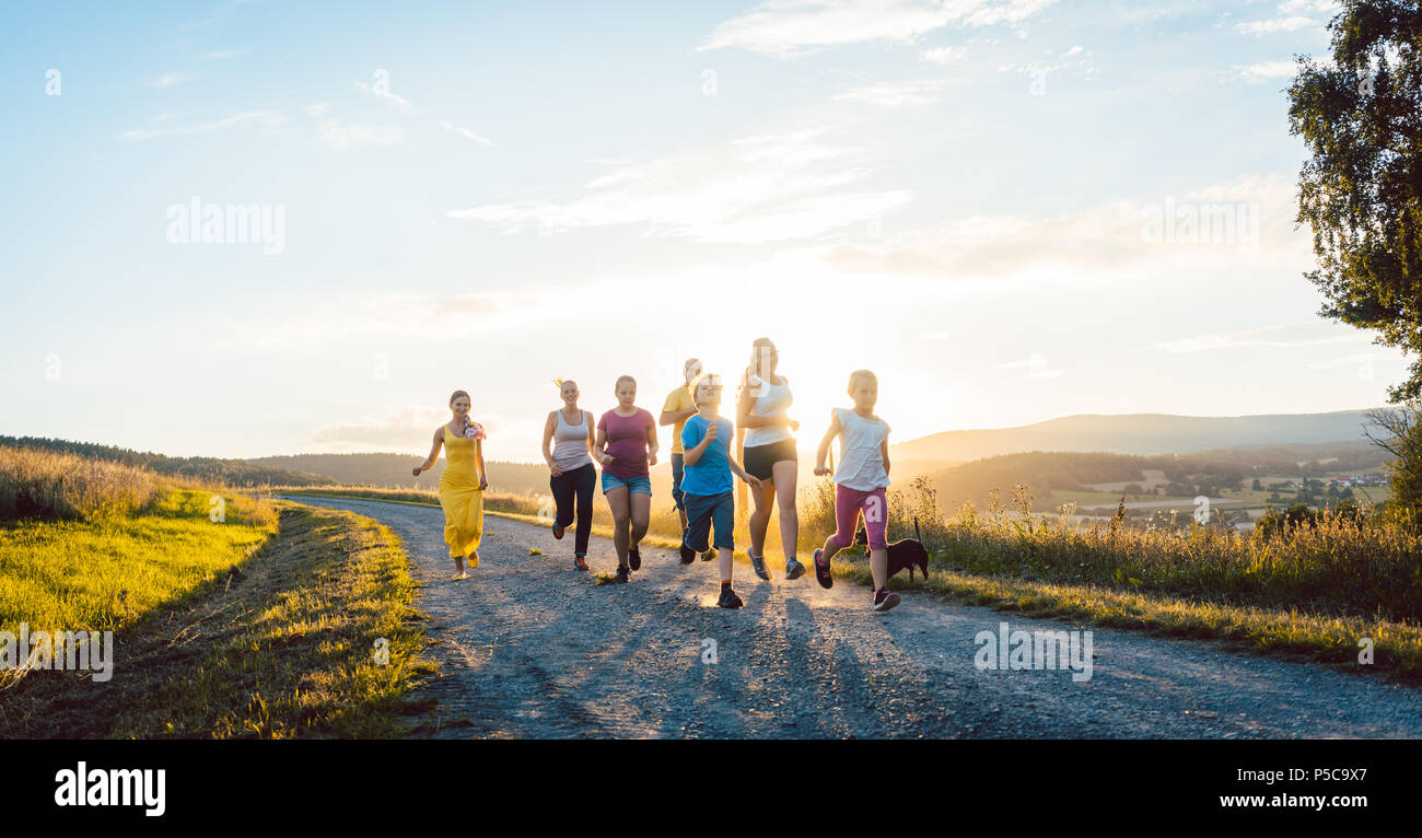 Playful family running and playing on a path in summer landscape Stock Photo