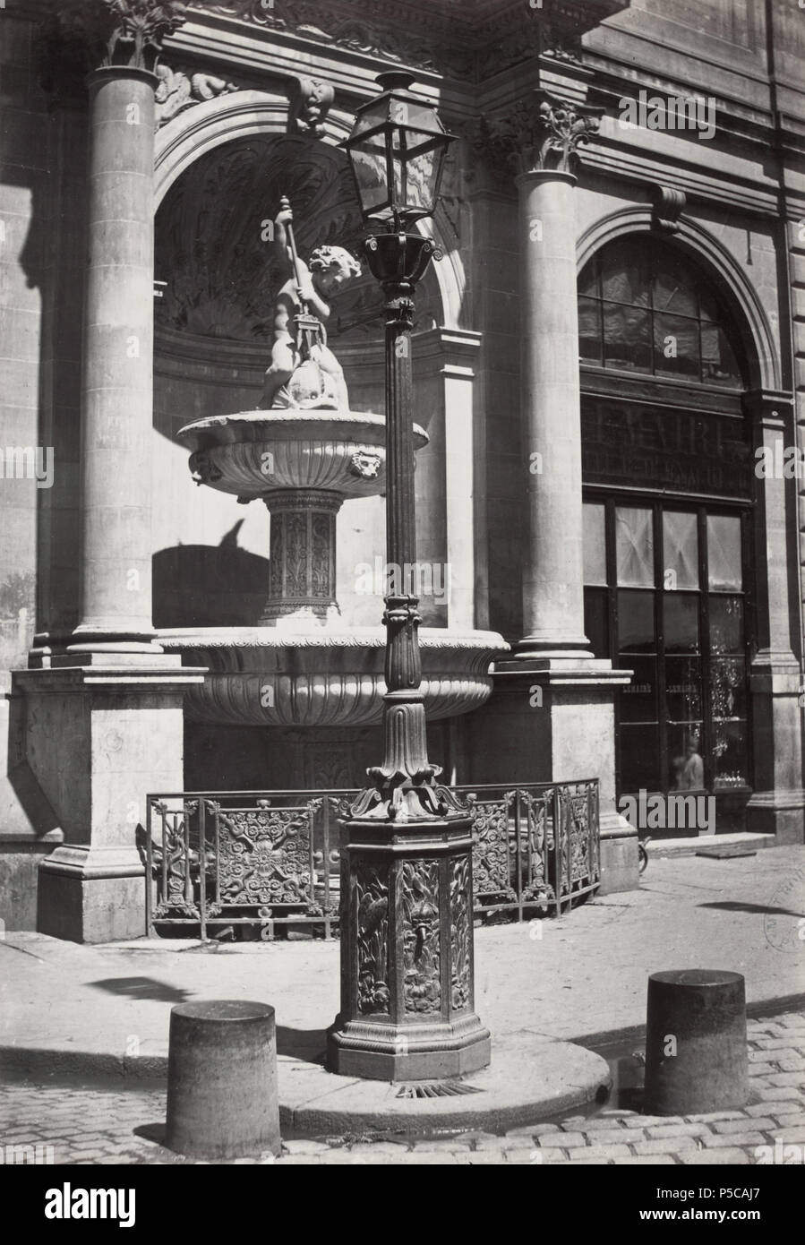 Fontaine Gaillon. no.31. English: Single globe with iron lamp post mounted on carved iron base, tap in base. A fountain in a wall niche with statue of a small boy spearing fish with a trident. 1878. N/A 327 Charles Marville, Fontaine Gaillon, 1878 Stock Photo