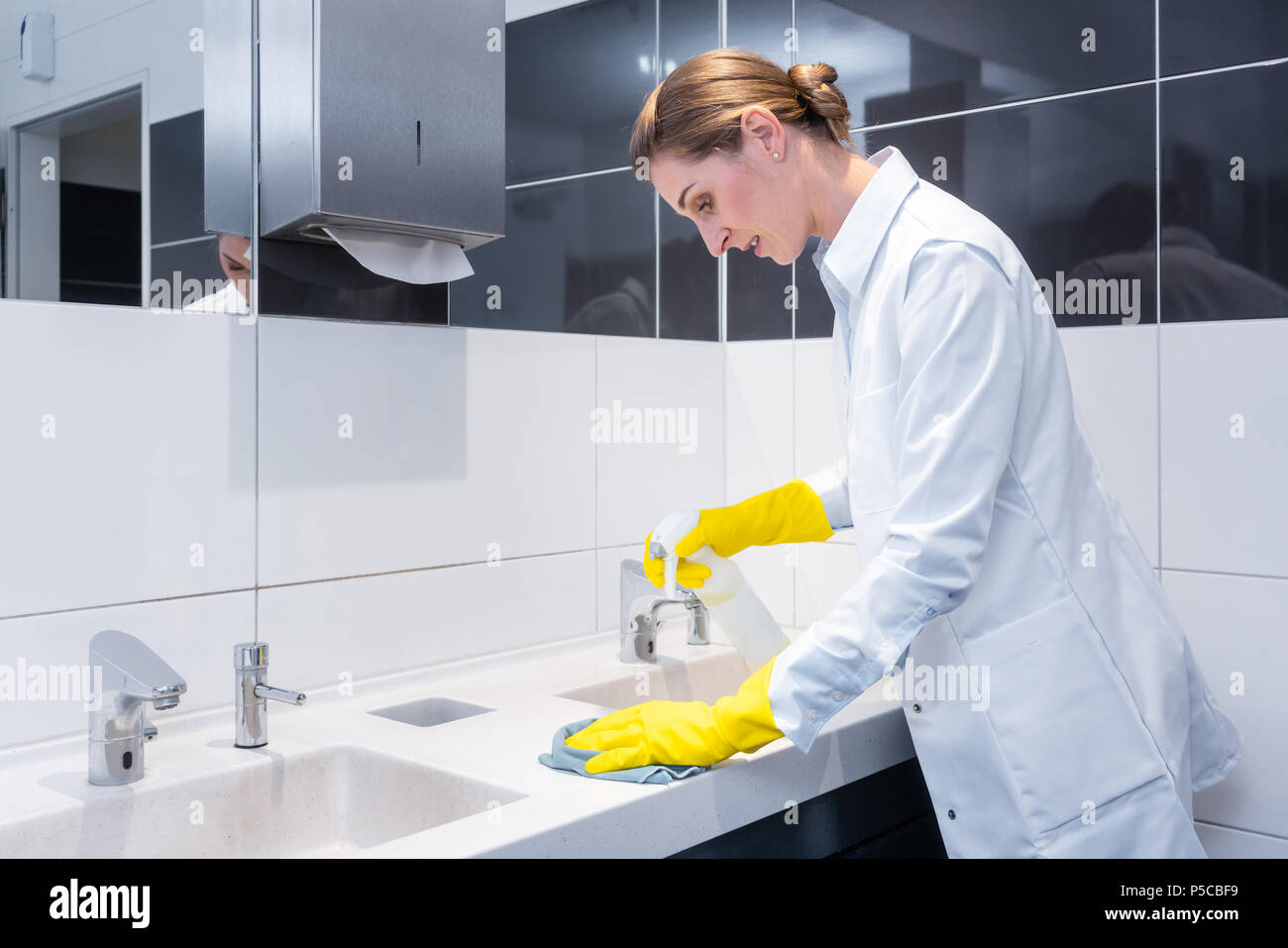 Janitor cleaning sink in public washroom  Stock Photo