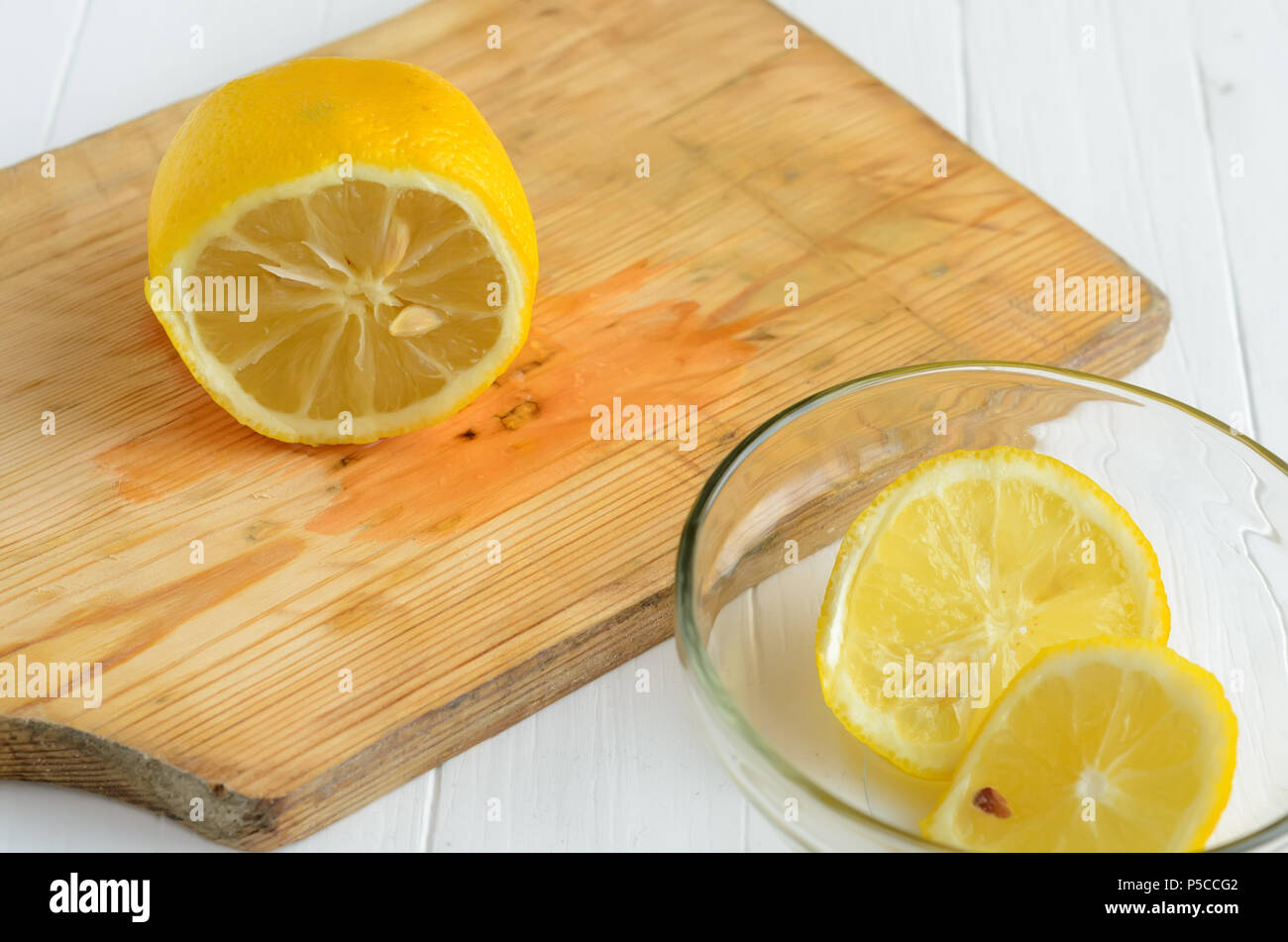 One cutted lemon on a chopping board.Two sliced of lemon into glass plate are down right angle. Stock Photo