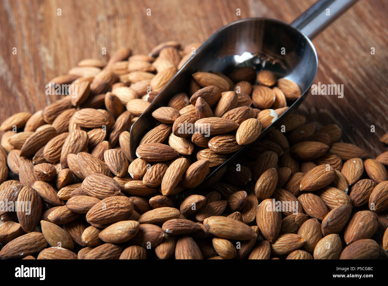 Hand Ful handful of almonds and scoop close up Stock Photo - Alamy
