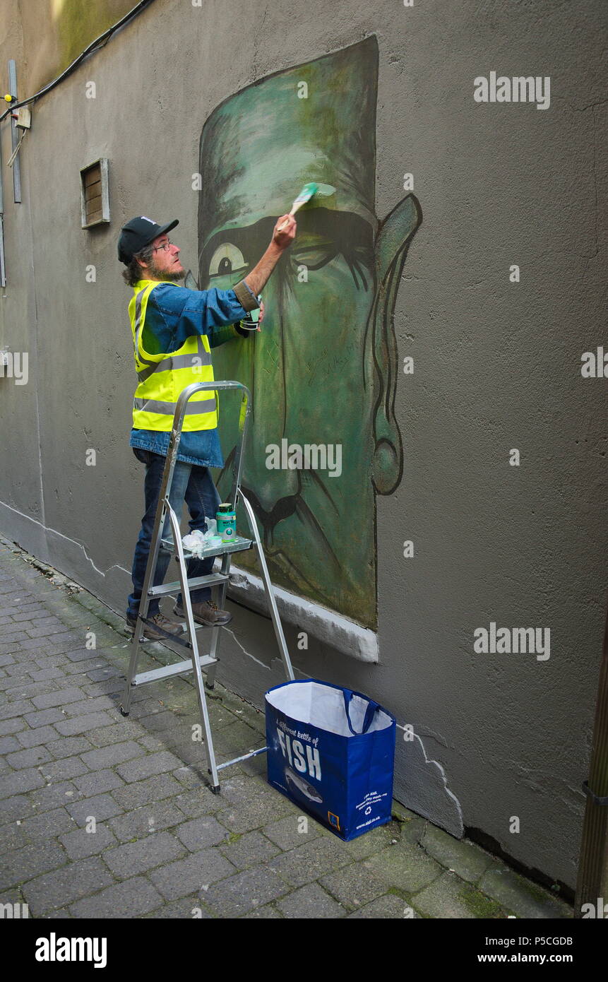 An artist restoring street art in Ennis Stock Photo Alamy