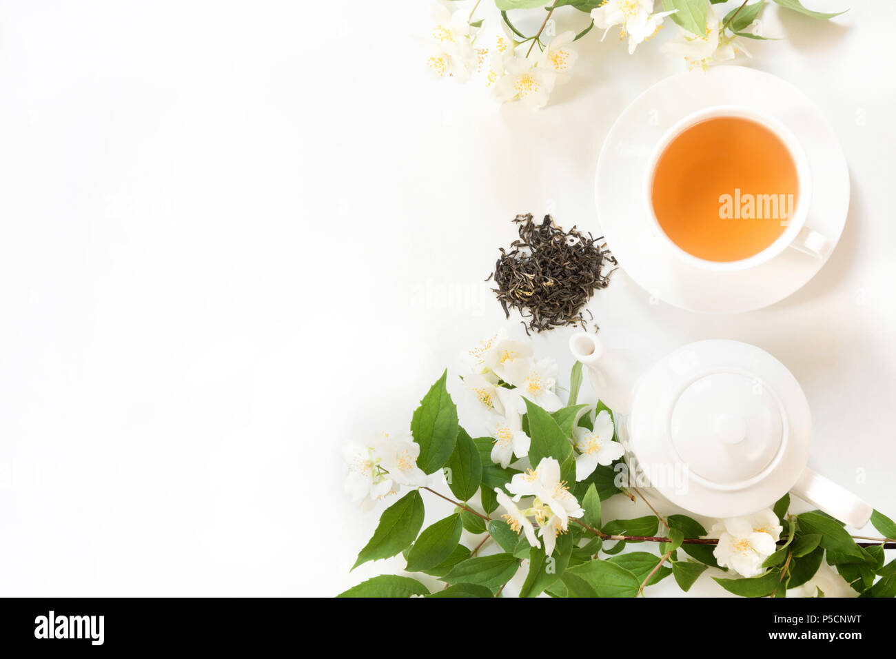 Green jasmin tea and jasmine flowers, cup of green tea on white. Top