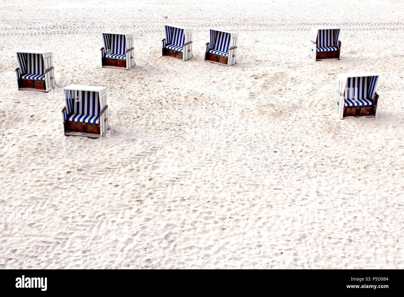 7 weiße Strandkörbe mit blau weiß gestreiften Bezügen, Polstern am weißen Strand von List, Sylt, Deutschland. Stock Photo