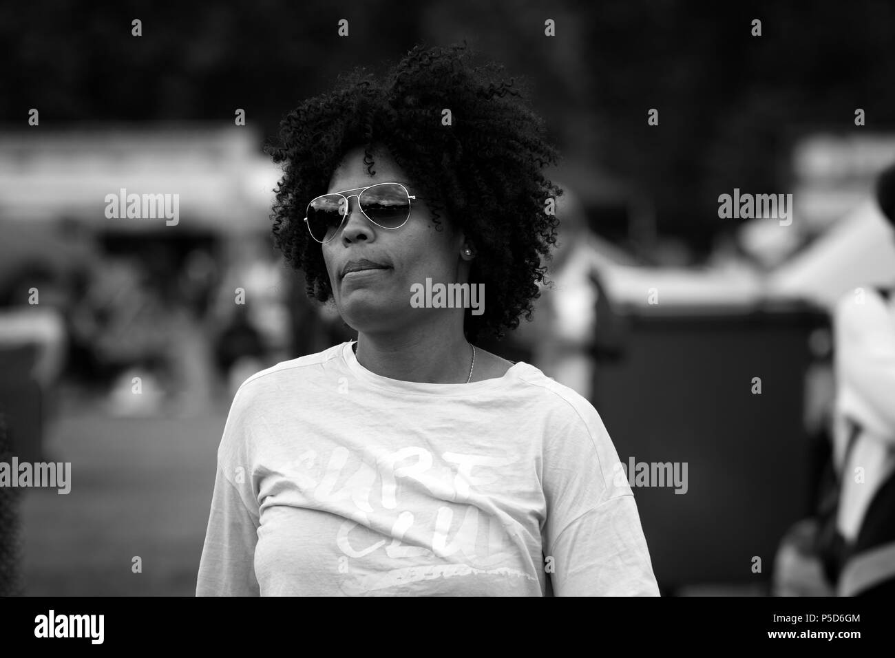 Candid Monochrome image of a beautiful black woman with curly afro hair dancing at the 2018 Africa Oye music festival in Sefton Park, Liverpool. Stock Photo