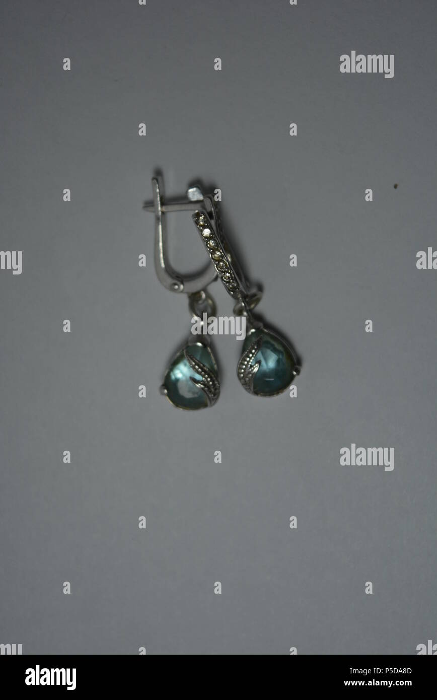 Jewelry, women's silver earrings with blue stones arranged on white background. Stock Photo