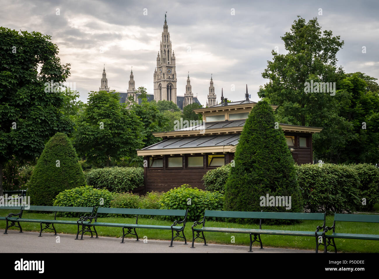 Benches, public toilet, trees and hedges in Volksgarten in Vienna (Austria) with City Hall in Backgounrd Stock Photo