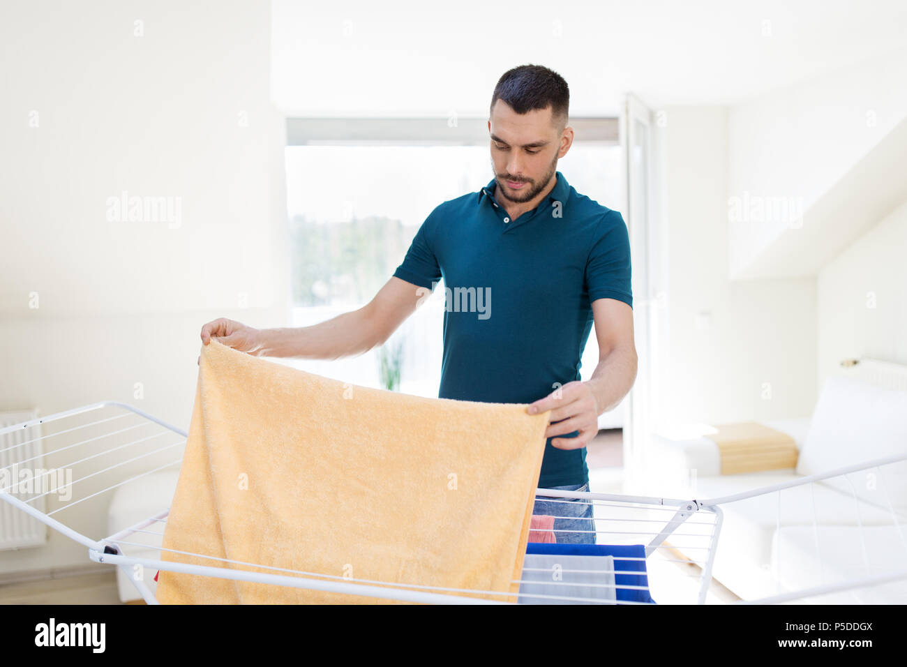 man taking laundry from drying rack at home Stock Photo