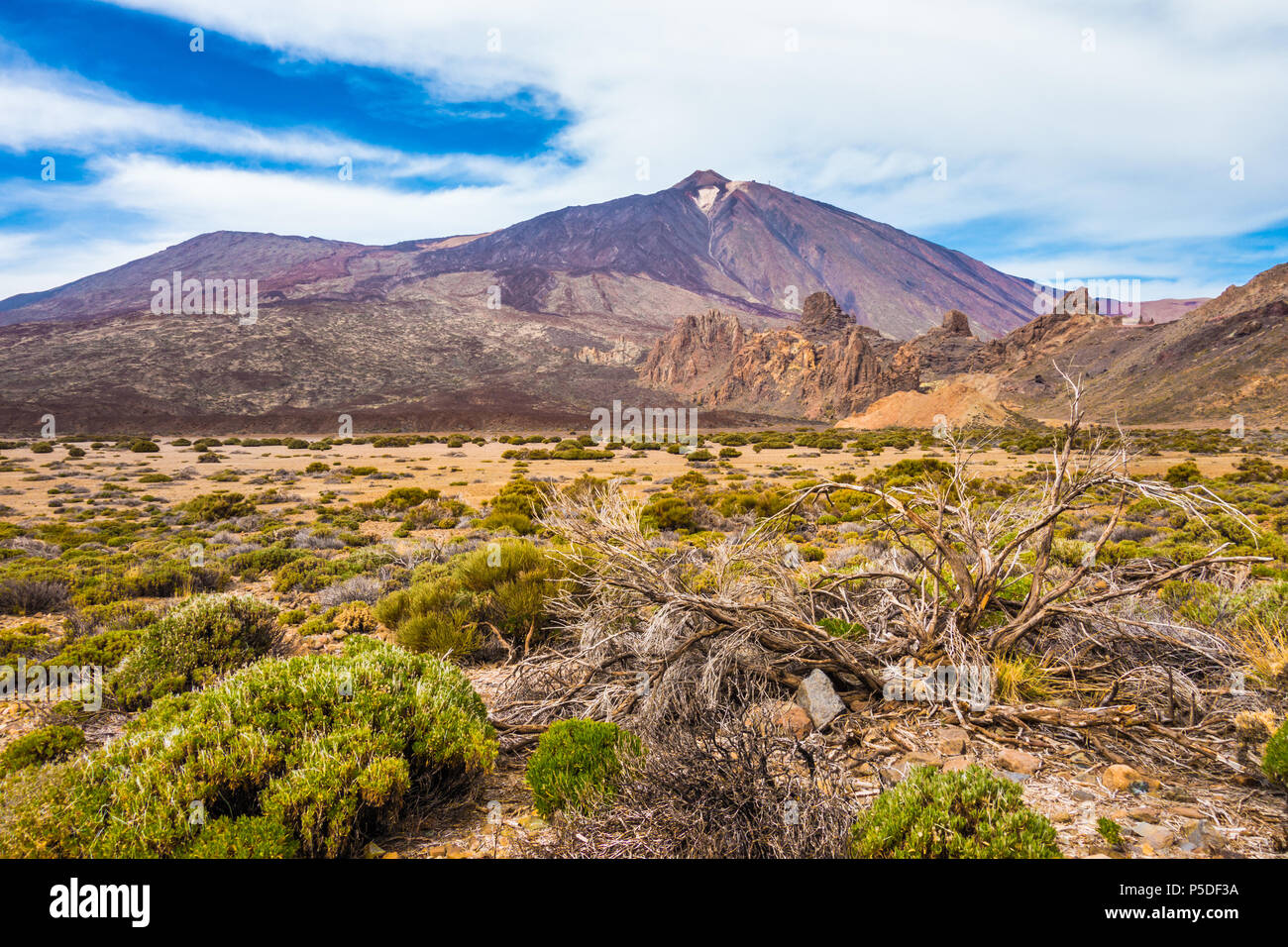 Panoramic view of barren scenery with famous Pico del Teide mountain volcano summit in the background on a beautiful sunny day with clouds, Teide Nati Stock Photo