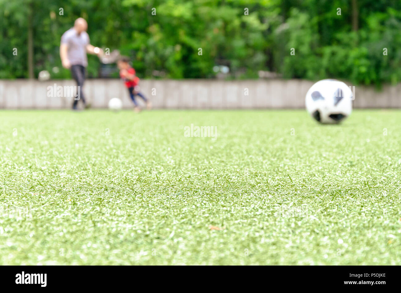 Football lawn, Father and kid playing in back. Soccer closeup detail wallpaper texture. Stock Photo