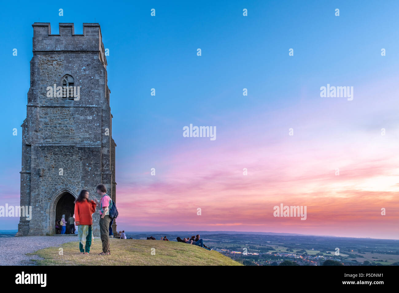 UK Weather - On top of Glastonbury Tor, a group of people gather to witness a beautiful  sunset over the Somerset Levels, as the West of England is se Stock Photo