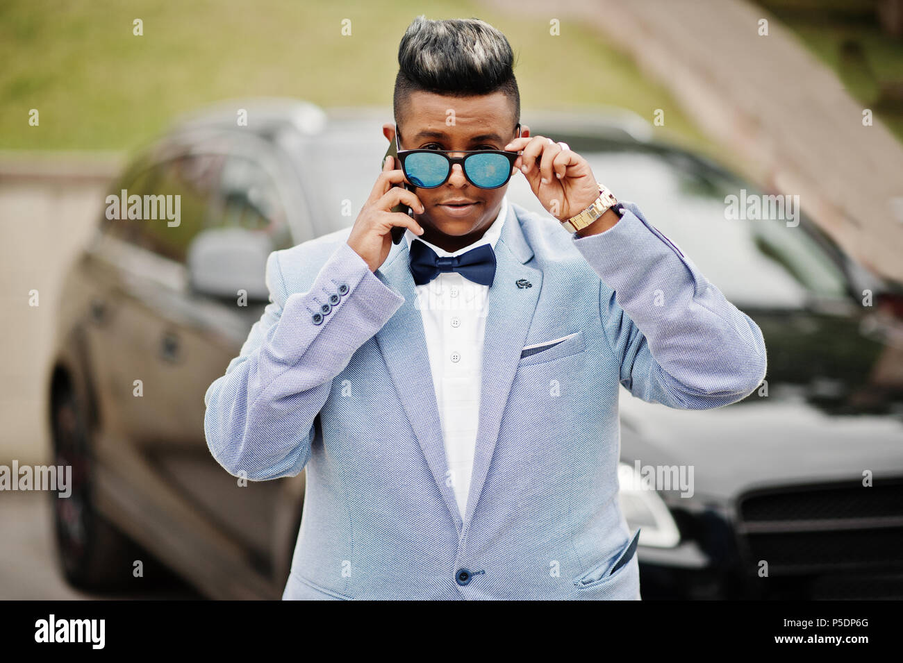 Stylish arabian man in jacket, bow tie and sunglasses against black suv  car. Arab rich businessman speaking on mobile phone Stock Photo - Alamy