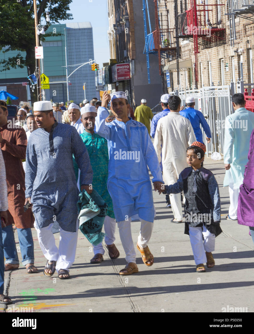 Muslim men pray on Eid on McDonald Ave in Brooklyn NY in the 'Little Bangladesh' Kensington neighborhood.  Eid al-Fitr 'feast of breaking of the fast') is an important religious holiday celebrated by Muslims worldwide that marks the end of Ramadan, the Islamic holy month of fasting (sawm). Stock Photo