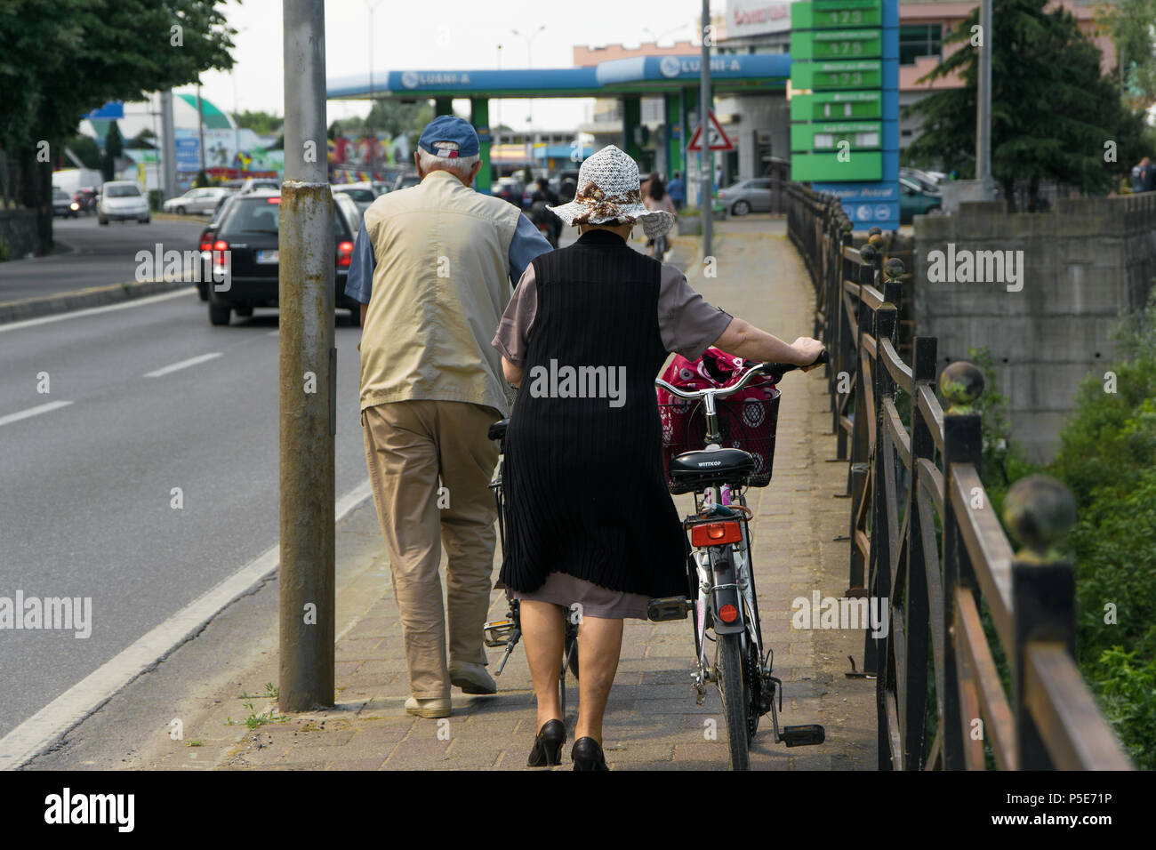 Couple of senior adult walk with bicycles on the sidewalk Stock Photo