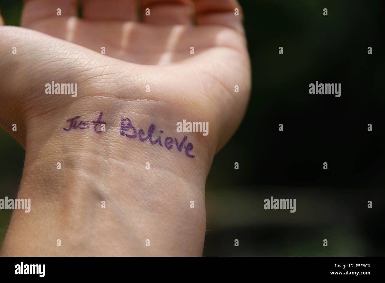 Handwritten motivational phrase on the human hand 'Just believe' Stock Photo