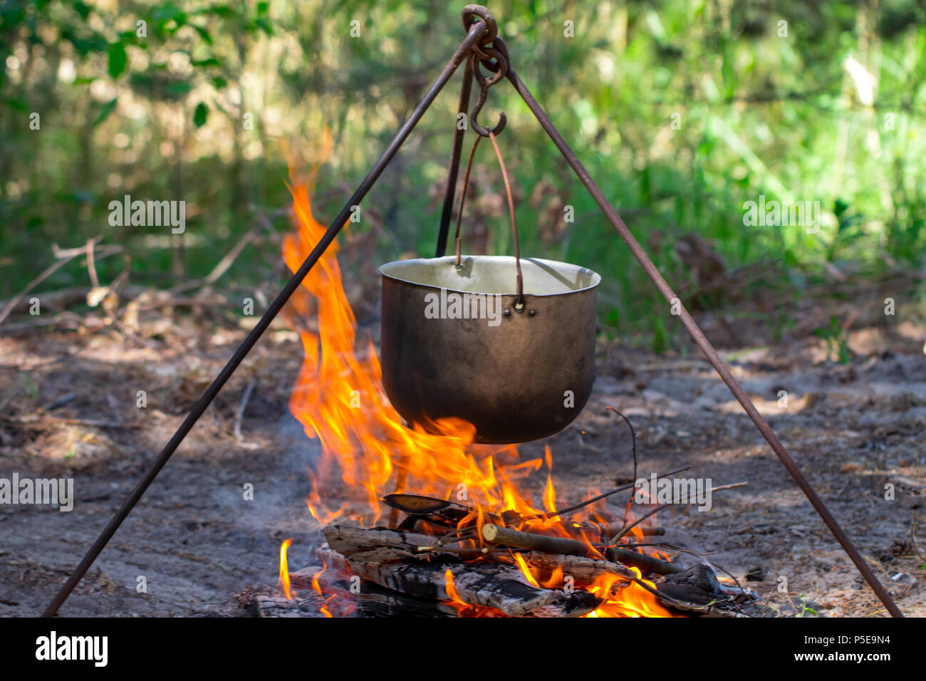 Tourist pot hanging over the fire on a tripod. Cooking in the campaign  Stock Photo - Alamy