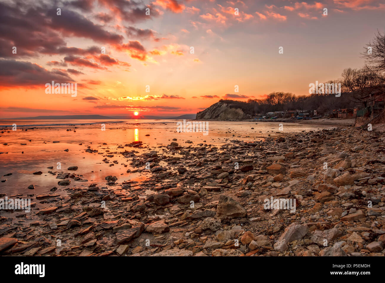 Exciting sunset/sunrise on the rocky coast with water reflection Stock Photo