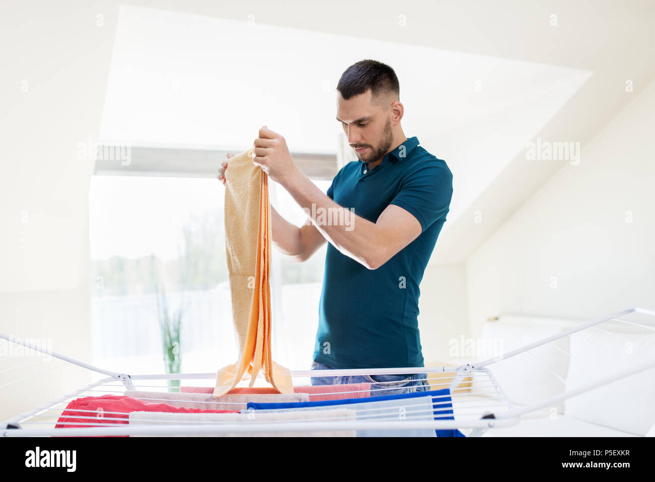 man taking laundry from drying rack at home Stock Photo