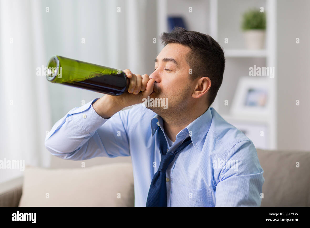 male alcoholic drinking wine from bottle at home Stock Photo