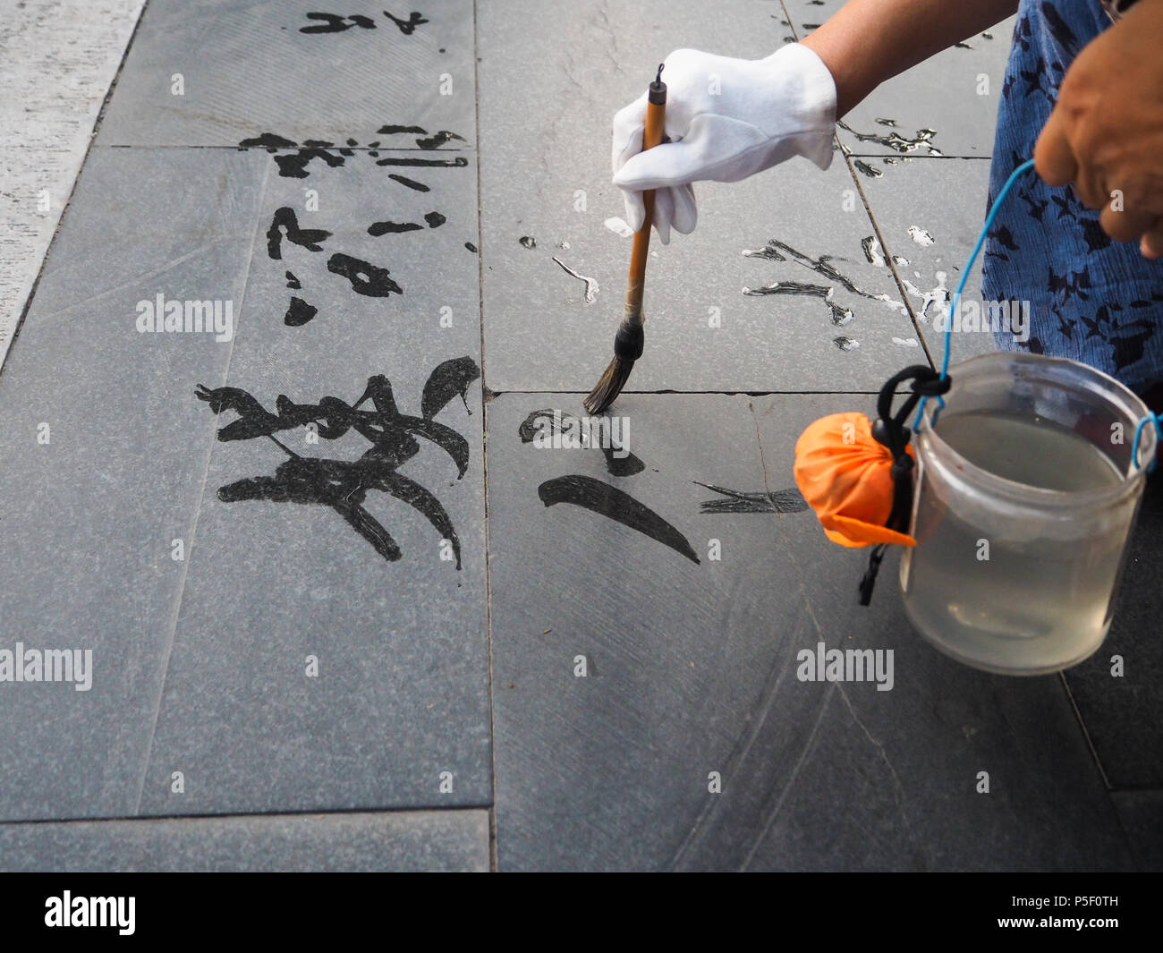 Older woman practicing calligraphy but due to the heat the Chinese