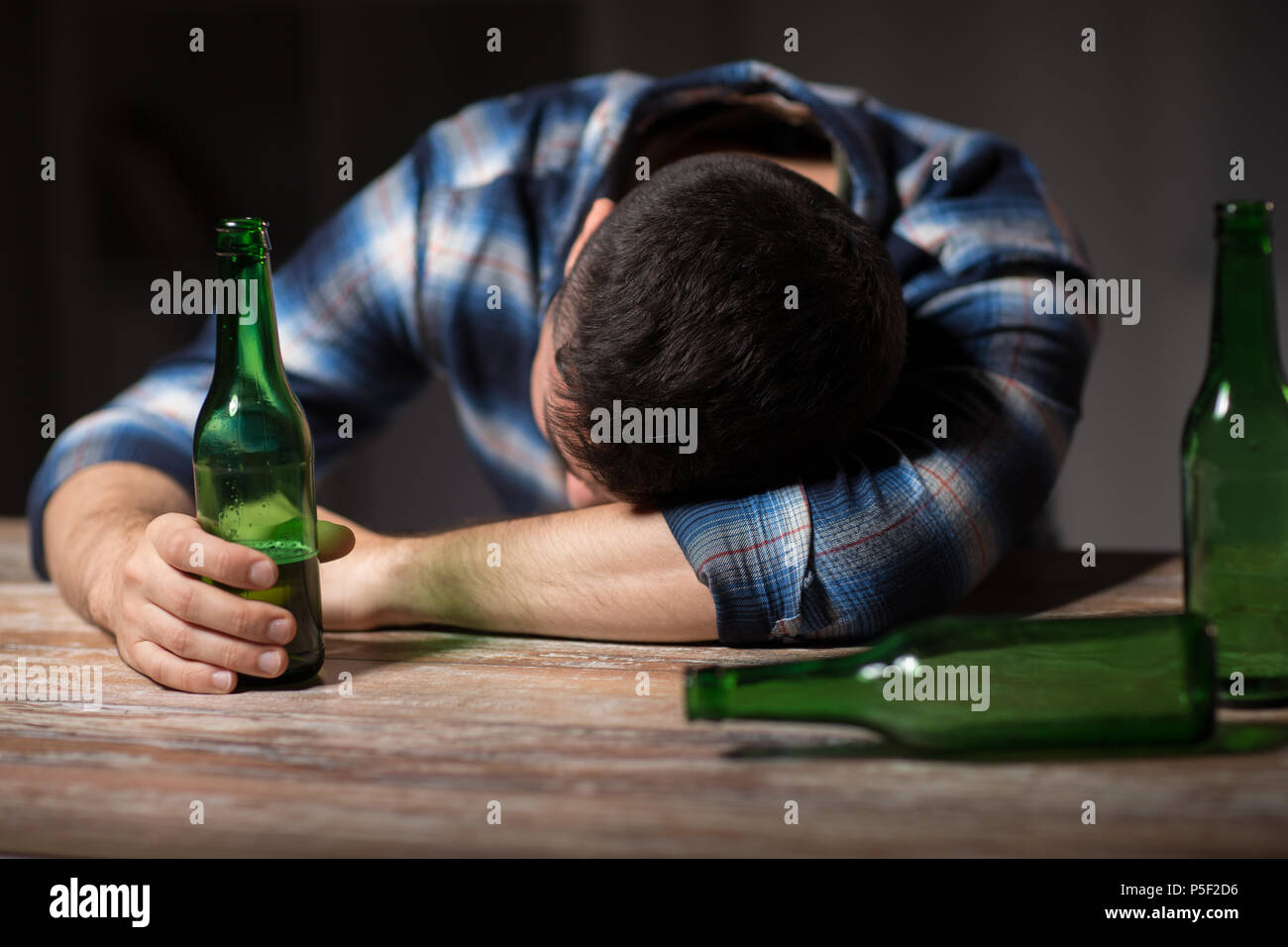 drunk man with beer bottles on table at night Stock Photo