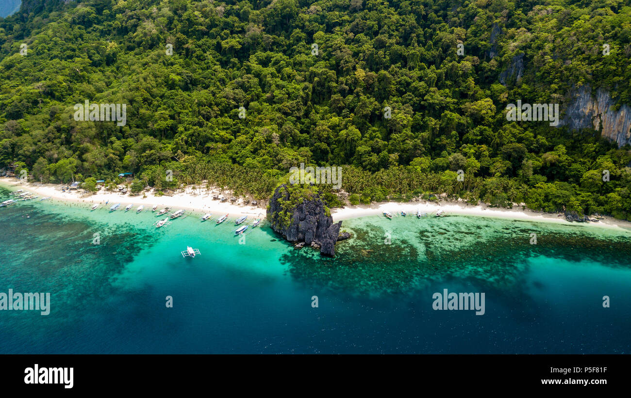 Aerial drone view of a spectacular tropical beach surrounded by dense jungle and jagged cliffs (Papaya Beach, Palawan) Stock Photo