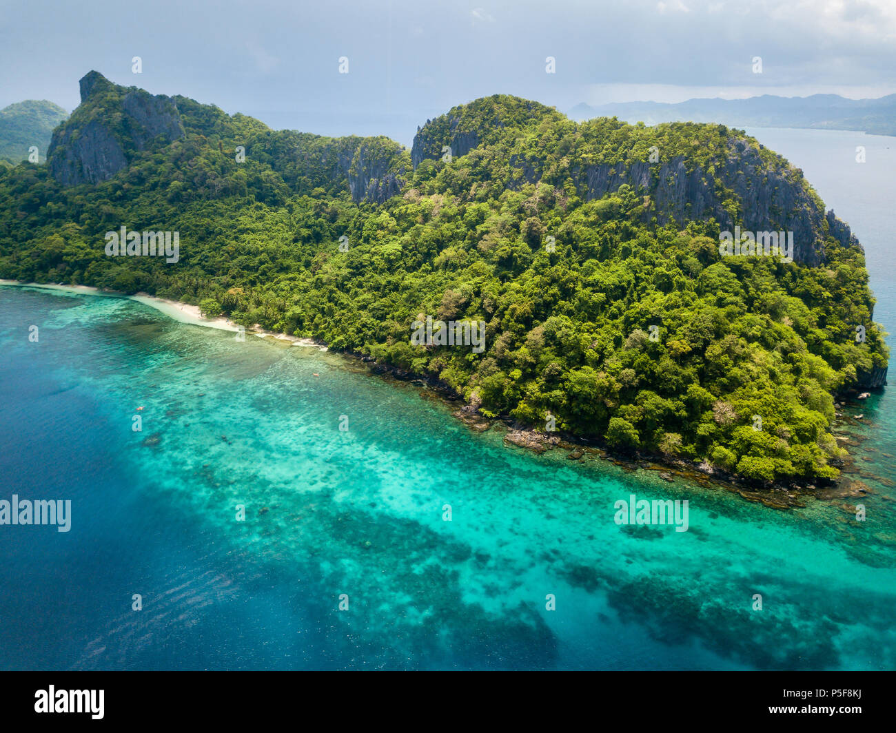 Aerial drone view of an unihabited tropical island with rugged mountains, jungle and sandy beaches Stock Photo