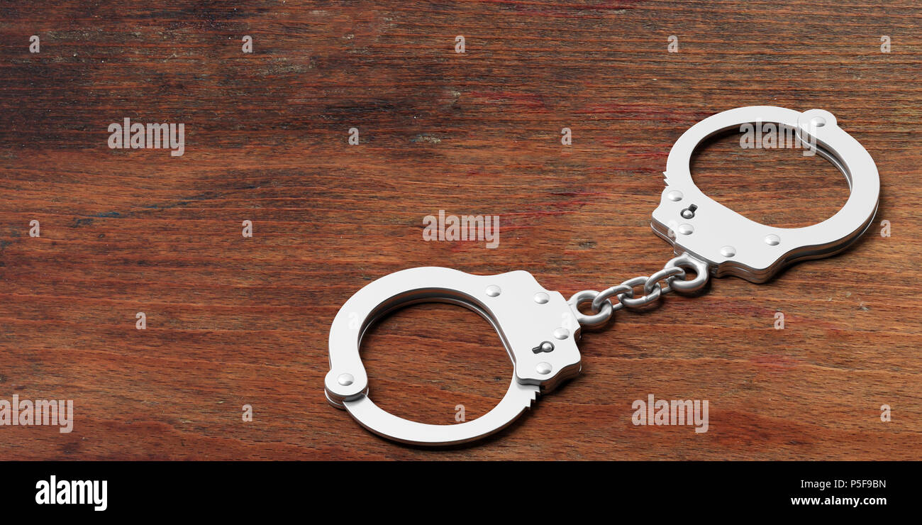 Metal police handcuffs isolated on wooden background, copy space, 3d illustration Stock Photo