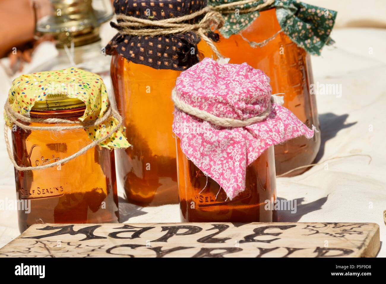 Glass jars, with fabric toppers held on by string, of maple syrup