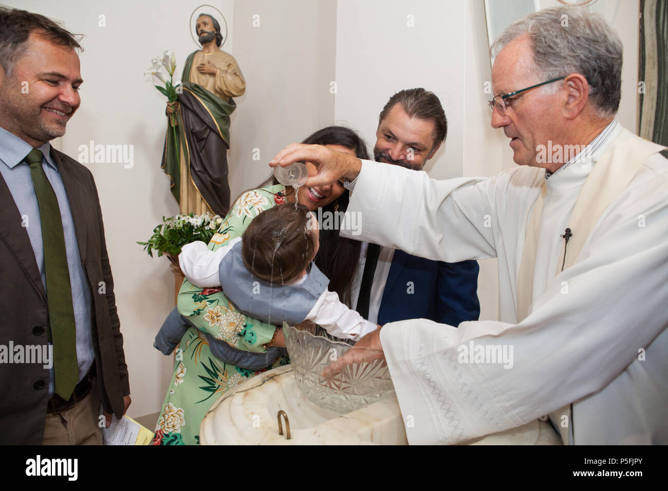 A baby boy is baptised by a priest in a Catholic Church Stock Photo