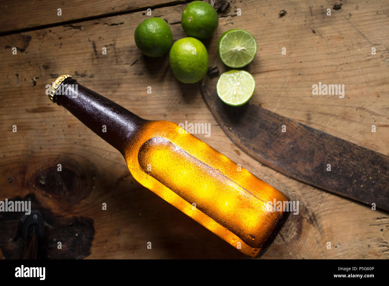 top view of a cold bottle of beer and lemons on a rustic wood table ...