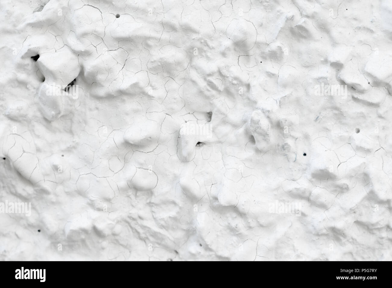 Rough Concrete Wall Decoration, Painted White. White Concrete Wall with Many Protruding Stones. Stock Photo