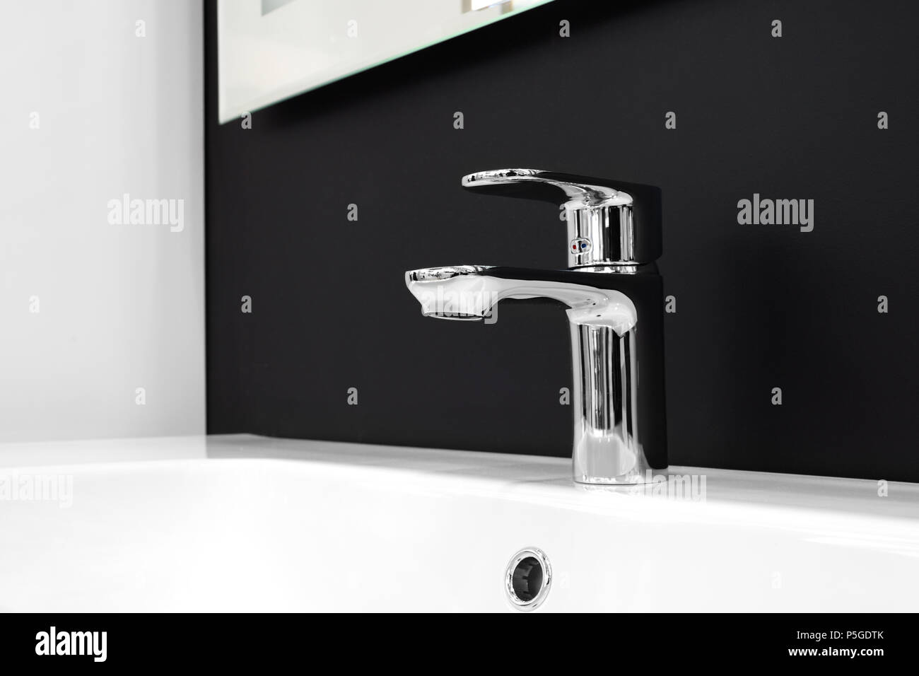 Luxury modern style faucet mixer on a white sink in a beautiful gray